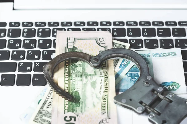 handcuffs on money on computer keyboard on table