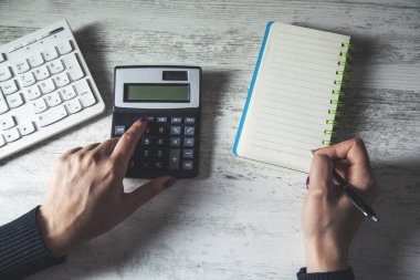 Masa arkasında hesap makinesi olan adam el kalemi