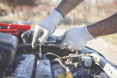Bir atölyede denetim ya da bakım sırasında araba motorundaki araçla el.