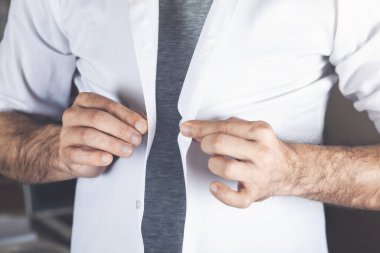 Genç adam odada beyaz kağıtları açıyor.