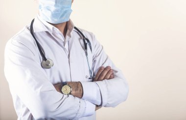 Kolları çapraz ve steteskopla poz veren kendinden emin bir doktor.