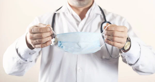 Genç doktor ya maskesini takar ya da çıkarır.