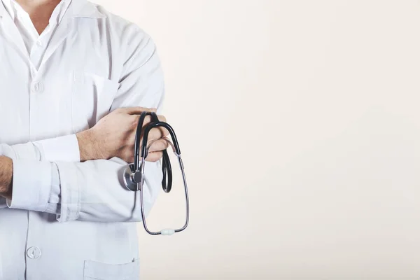 Kolları çapraz ve steteskopla poz veren kendinden emin bir doktor.