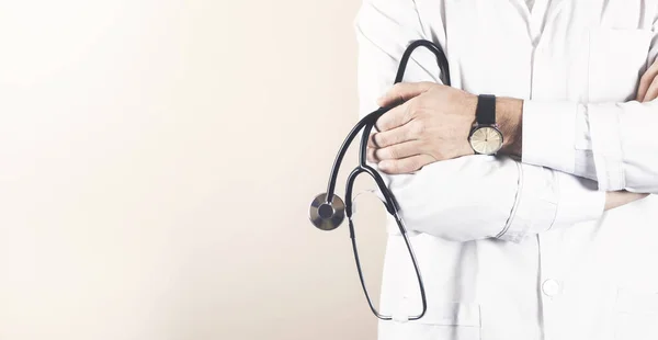 Kolları çapraz ve steteskopla poz veren kendinden emin bir doktor.