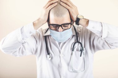 Çaresiz doktor kafasını elinde tutuyor.