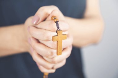 Elinde tahta haç olan genç bir kadın.