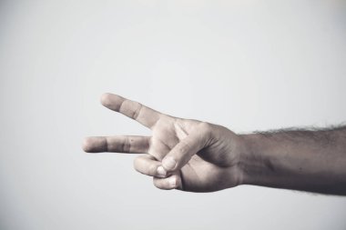 Adam gri arka planda zafer işareti gösteriyor.