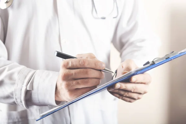 Erkek doktor hastanedeki panoya notlar yazıyor.