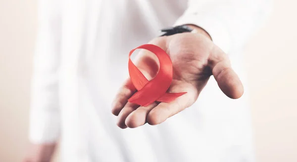 Dünya AIDS Günü için doktorun elindeki kırmızı kurdeleye yardım eder
