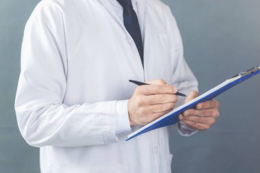 Erkek doktor hastanedeki panoya notlar yazıyor.