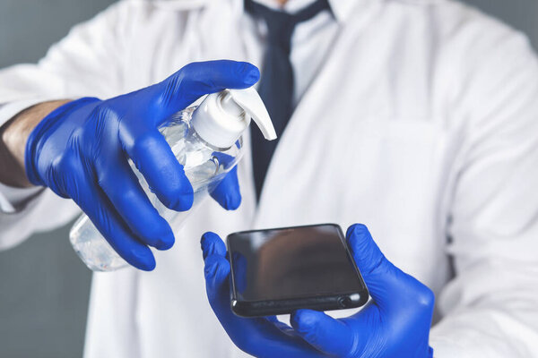 A person disinfects the phone with an antiseptic to protect themselves from covid-19 infection