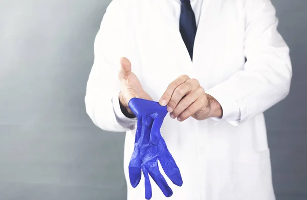 Doctor Masculino Poniendo Guantes Médicos Látex Azul Sobre Fondo Gris —  Fotos de Stock