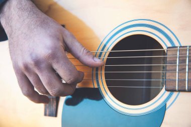 Doğada gitar çalan genç bir adamın yakın çekimi..