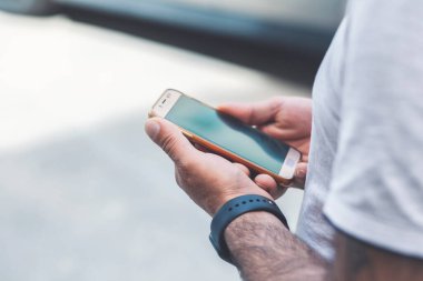 Elinde telefon tutan genç bir adam. 