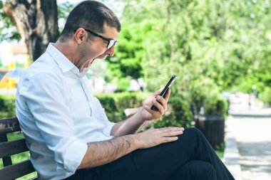 Genç adam parkta telefona bağırıyor.