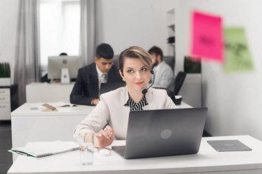 Ofiste dizüstü bilgisayarla çalışan gülümseyen kadına odaklan.