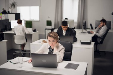 Genç kadın bir dizüstü bilgisayar üzerinde çalışıyor.