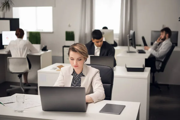 Frau und ihre Kollegen sitzen an einem Tisch mit Laptop — Stockfoto