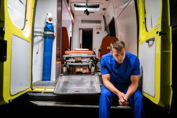 Мужчина в медицинской форме сидит на машине скорой помощи — стоковое фото