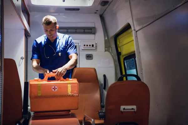 Санитар в машине скорой помощи и открывает медицинскую сумку с эквивалентом — стоковое фото