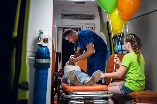 Машина скорой помощи, парамедик надевает кислородную маску на женщину, лежащую на носилках — стоковое фото