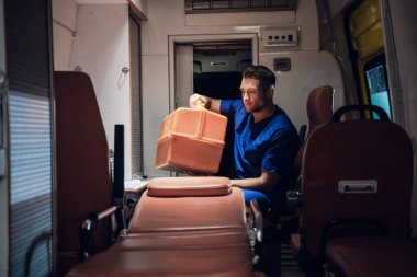 Corpsman sits in the ambulance car and packs medical bag