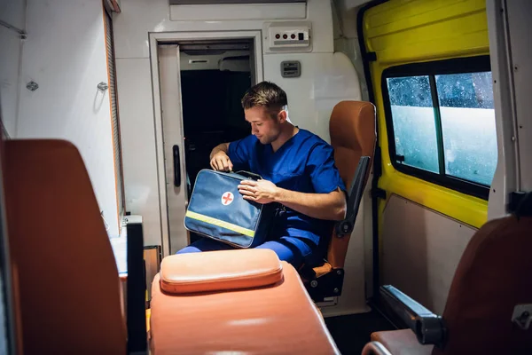 Corpsman sits in the ambulance car and holds medical bag — 图库照片