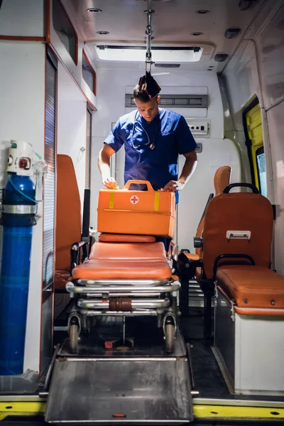 Jeune homme en uniforme médical emballe sac médical dans la voiture d'ambulance — Photo