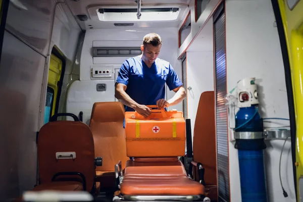 Молодой доктор упаковывает медицинскую сумку в машину скорой помощи — стоковое фото
