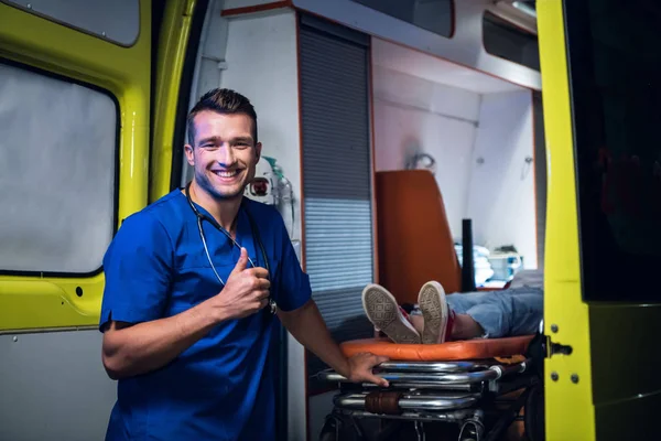 Doctor en uniforme médico y sonrisas en el coche de la ambulancia —  Fotos de Stock