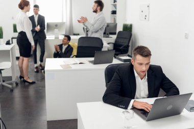 Men and woman have a break time during working day in the office, focus on young man working on laptop