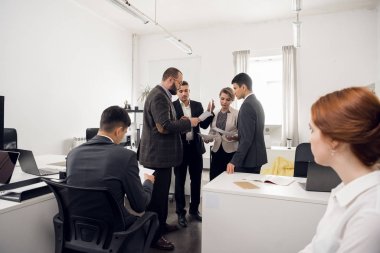 Working day in office, workers stand and look at the documents