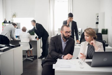Office workers talk about something, man talks on phone, other three work at a table on backgorund