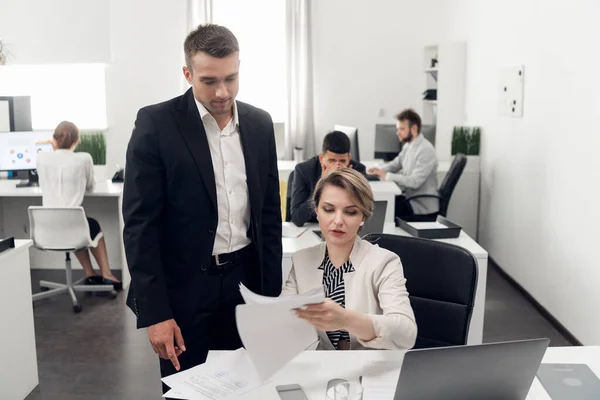 People work in the office, man in stand over the woman and look at documents — 스톡 사진