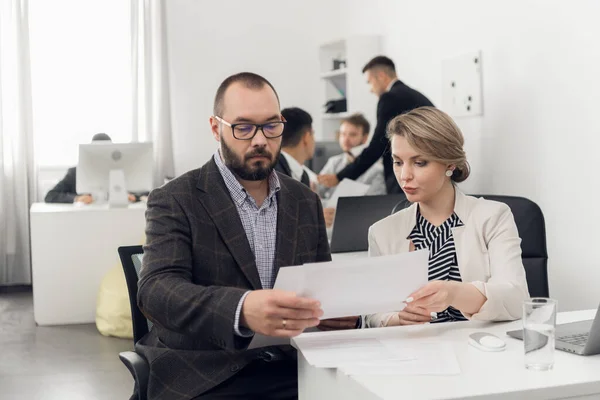 Chief discusses the documents with his young colleague sitting at a table in the office — Stock Photo, Image