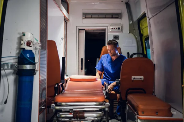 Молодой врач в медицинской форме сидит в машине скорой помощи — стоковое фото