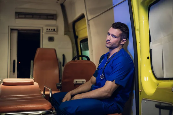 Un forense cansado y triste se sienta dentro del coche de la ambulancia —  Fotos de Stock