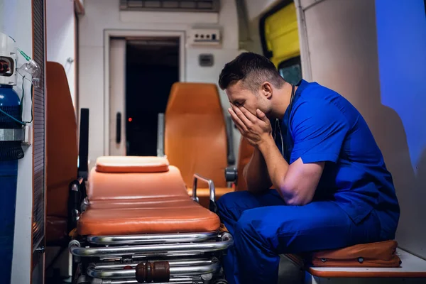 Le corps fatigué en uniforme médical se trouve à l'intérieur de l'ambulance — Photo