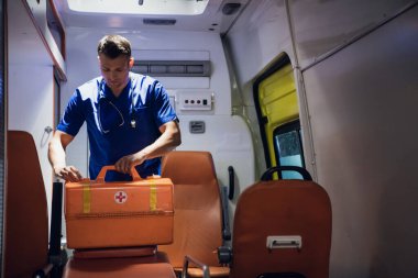 Sıhhiyeci ambulans vagonunda tıbbi çantayı kapatır.