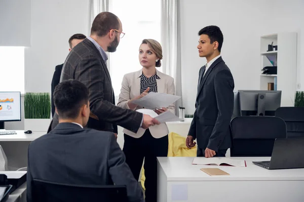 Colleages stand around in the office, woman looks at her chief and listens — 스톡 사진