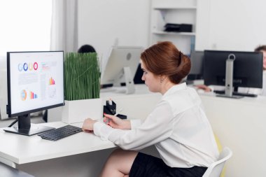 Young woman sits at a table and works on computer
