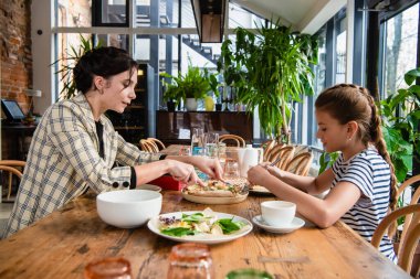 Anne ve kızı Lanch 'te sohbet ediyor, yemeğini paylaşıyor.