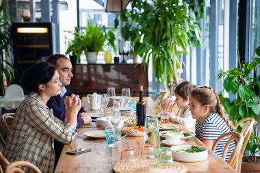 Gülümseyen aile mutfakta birlikte yemek yiyor.