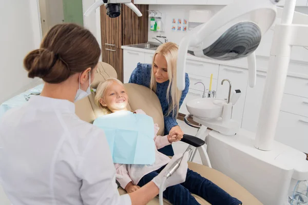 A child with a mother at a dentistrys room. The female child lies in the chair, her mother is behind — Stock Photo, Image