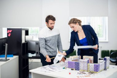 Genç mimar bürosu çalışanları inşaat projesini tartışıyor.
