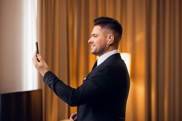 Joven viajero de negocios en un traje haciendo una videollamada después de llegar al hotel — Foto de Stock