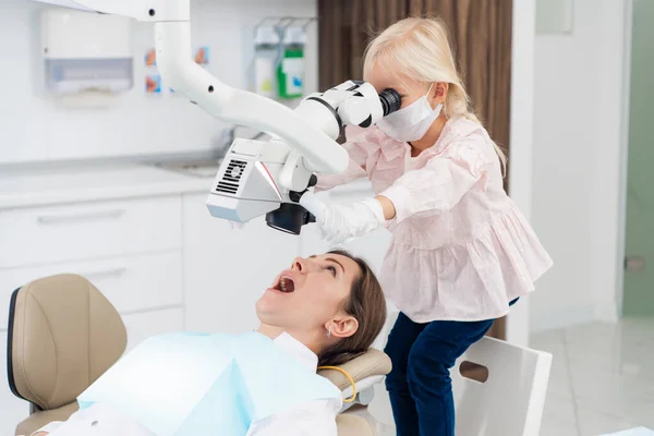 Dziewczyna bawiąca się sprzętem stomatologicznym podczas pierwszej wizyty u stomatologa dziecięcego — Zdjęcie stockowe