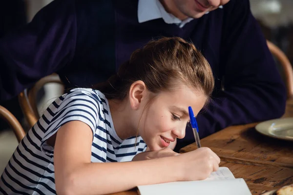 Ein Mädchen schreibt etwas in ihr Notizbuch — Stockfoto