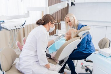 Annesiyle diş kontrolü yaptıran bir çocuk.