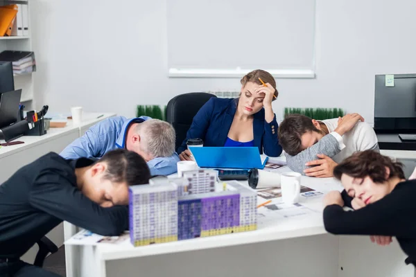 A young business woman trying to concentrate in the office, while her colleagues are having a rest at the meeting table — Stock Photo, Image